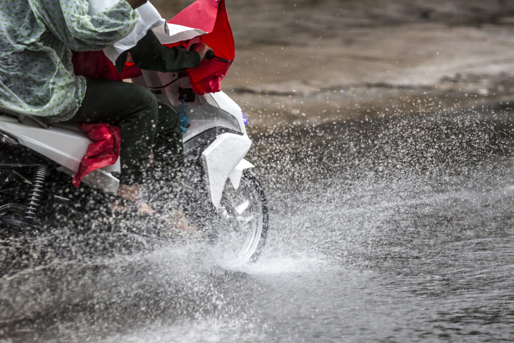 Una moto pasa por encima de un charco: las condiciones de lluvia pueden ser perjudiciales 